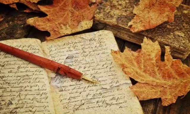 Plume et cahiers anciens entourés de feuilles mortes, pour écrire un conte de fée ou des légendes traditionnelles.